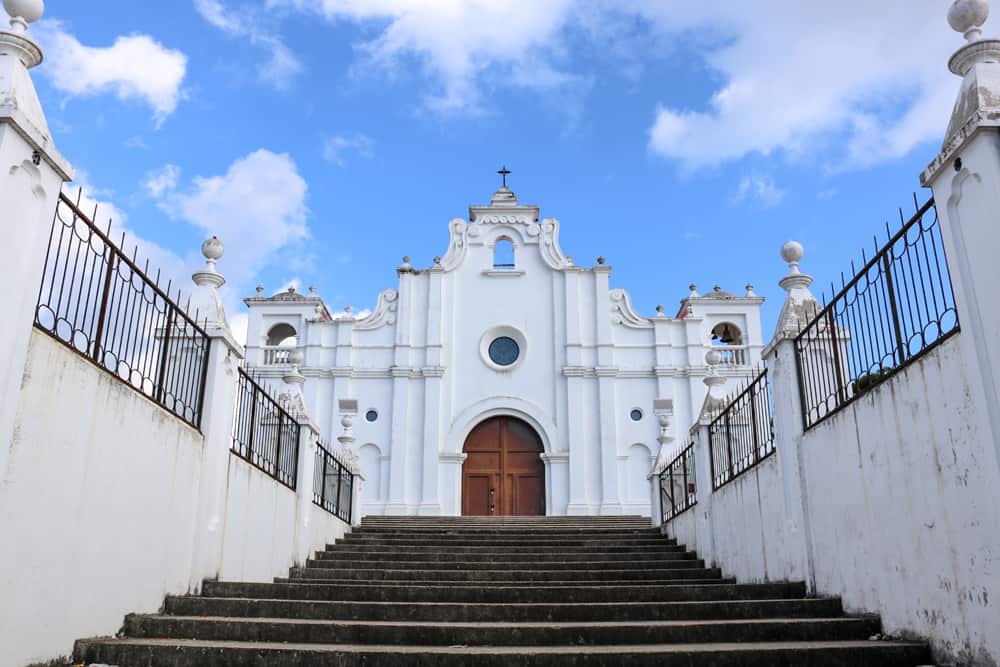 Stairs leading up to the front of a large, white, colonial church.