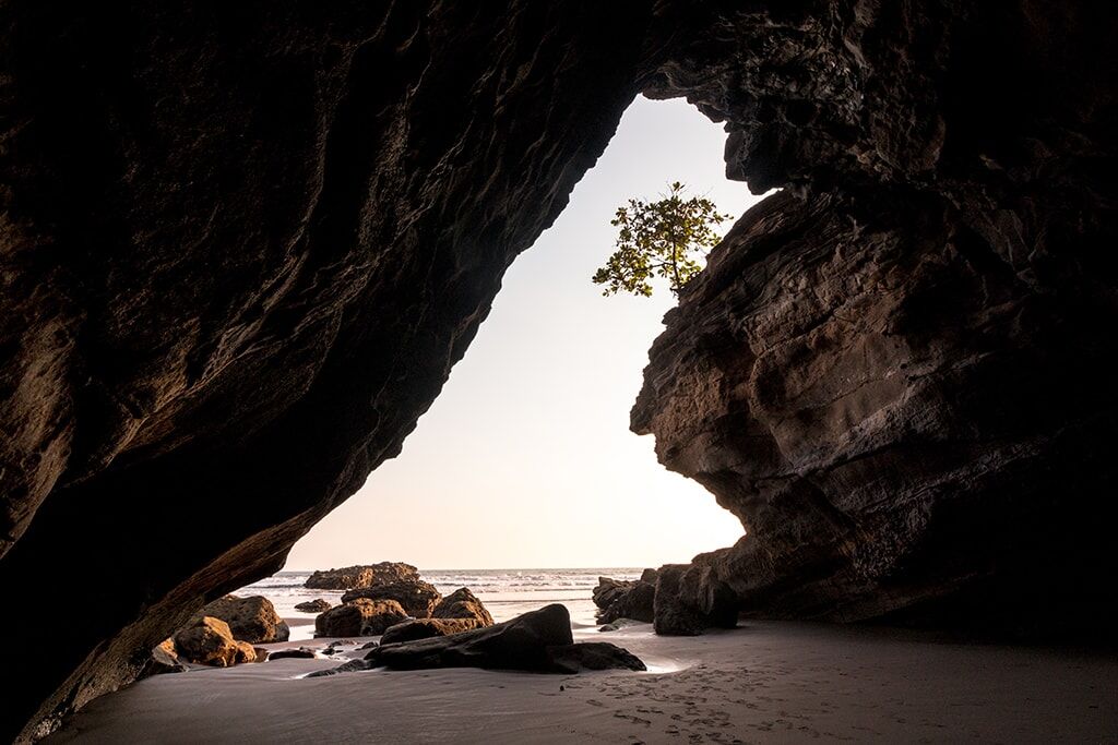 Looking out of a cave over the ocean at sunset.