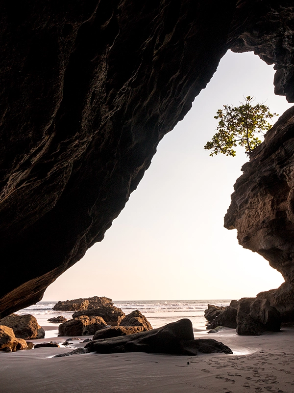 Looking out at a sunset over the ocean from within a cave.
